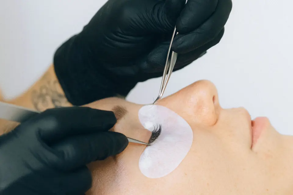 Een gesloten oog met een pad eronder, de wimpers worden behandeld